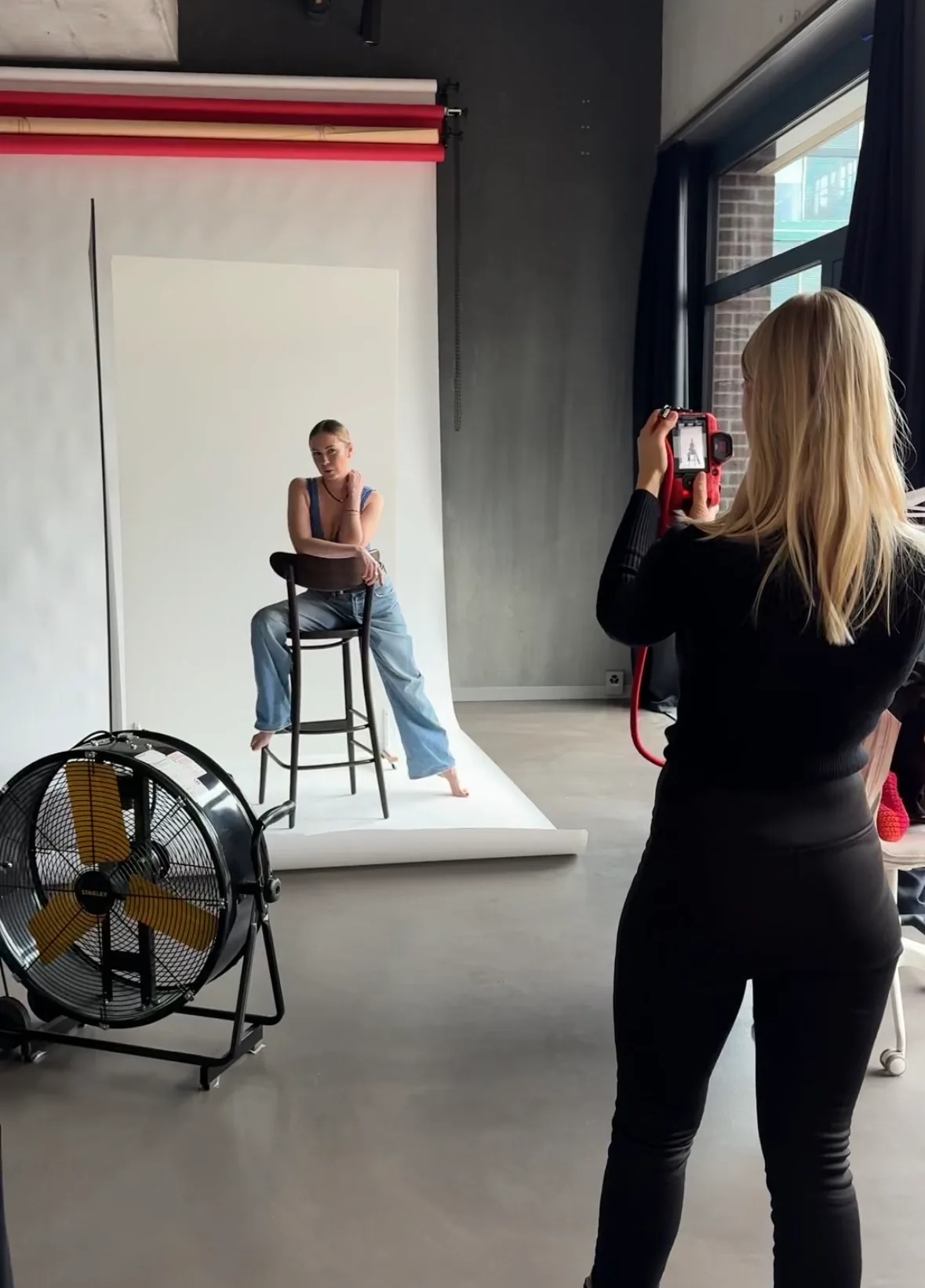 Photographer shooting a model against a white backdrop in the dibe studio.