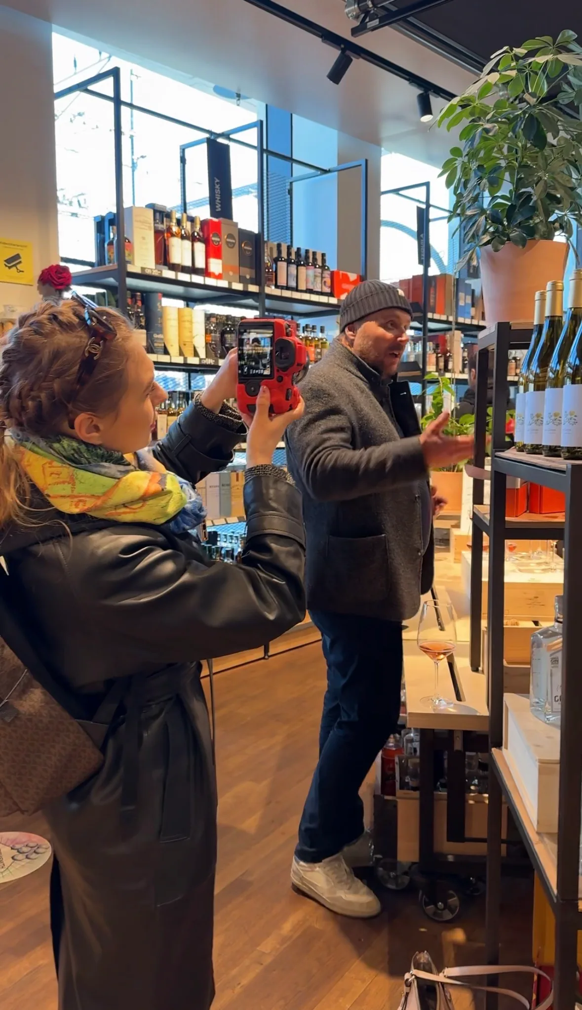 Content production in-store: filming with a red camera among the wine shelves.